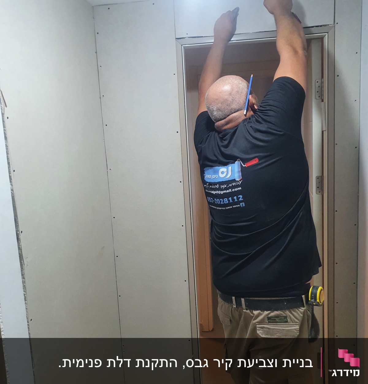 אדם מתקין לוח גבס עם מברגה